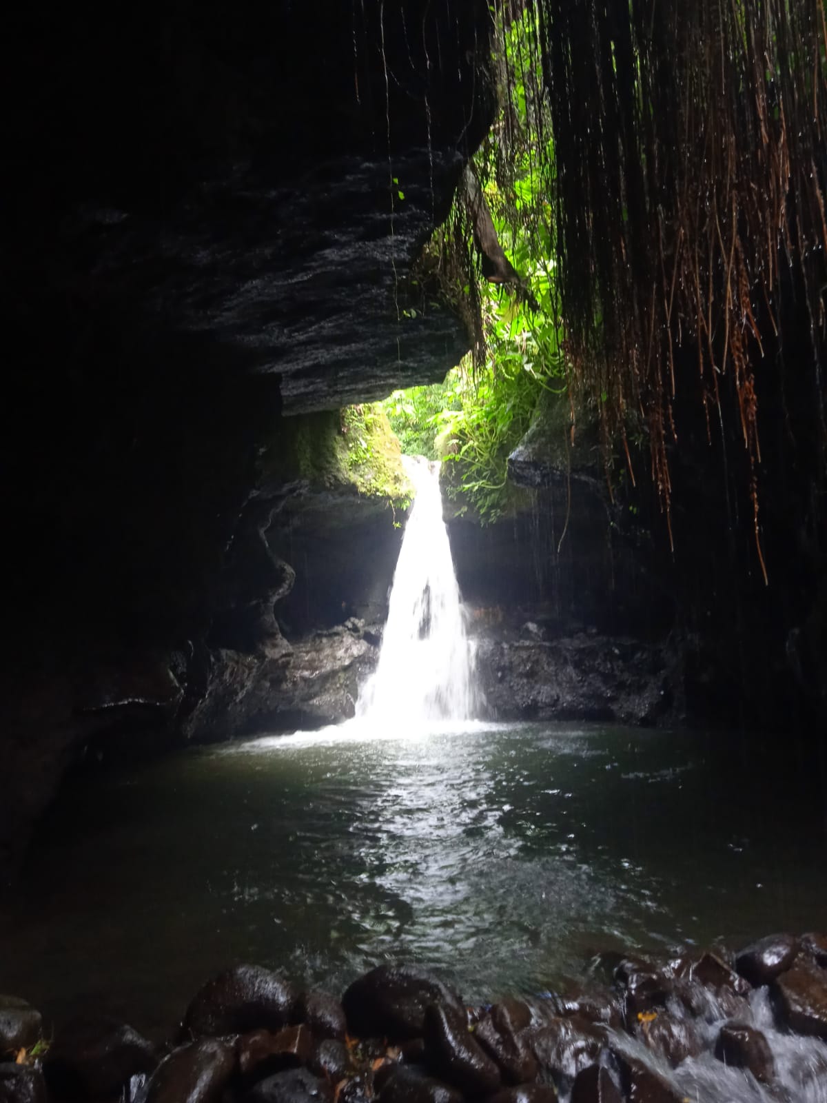 Dramatic waterfall inside a dark cave grotto in Tetebatu